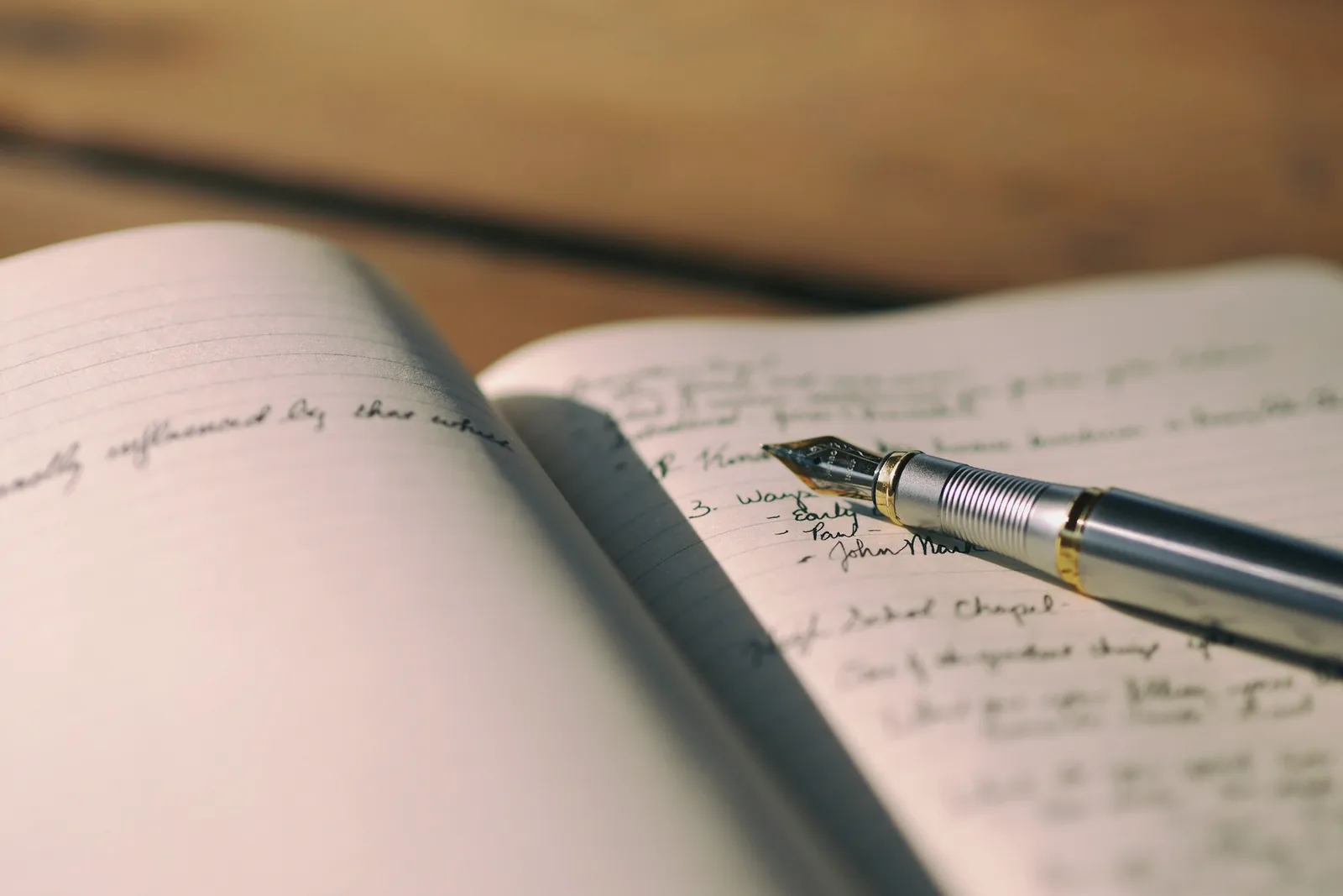 Carnet ouvert couvert d'une écriture manuscrite, stylo plume posé sur la page